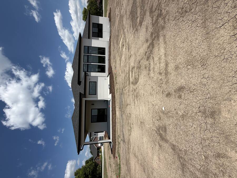 Painted gray and white lap siding on the front of a new-construction home with covered patio